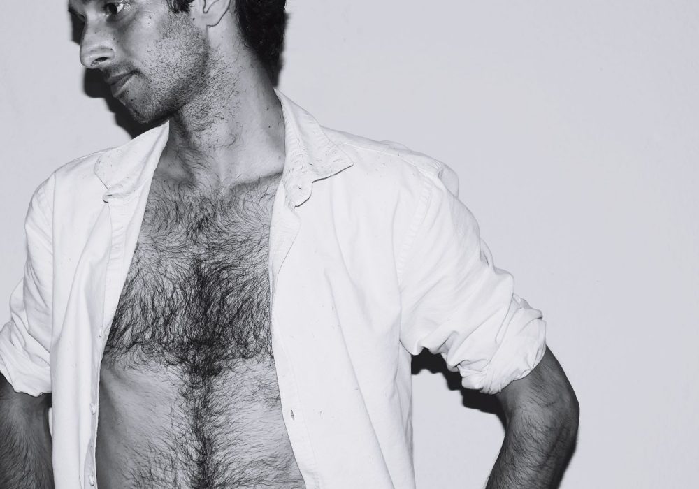 thoughtful-man-with-fully-unbuttoned-shirt-against-white-background